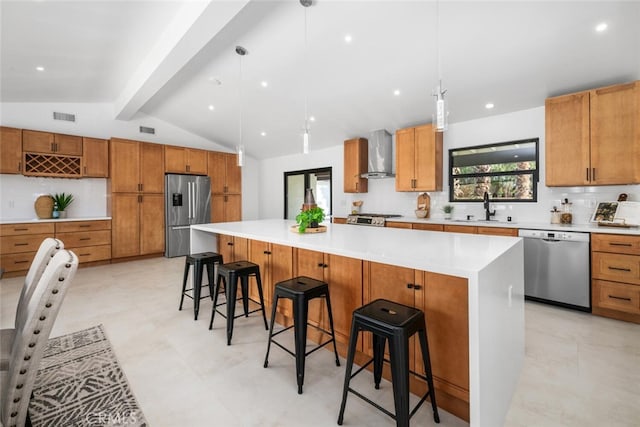 kitchen with a spacious island, a breakfast bar, hanging light fixtures, appliances with stainless steel finishes, and wall chimney exhaust hood