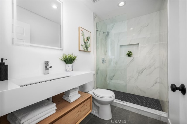 bathroom featuring sink, toilet, a tile shower, and tile patterned flooring