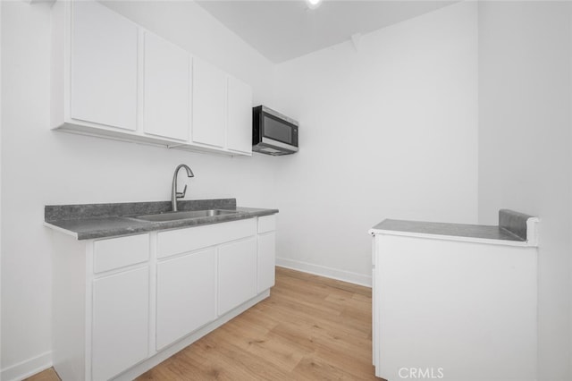 kitchen featuring sink, white cabinetry, and light hardwood / wood-style flooring