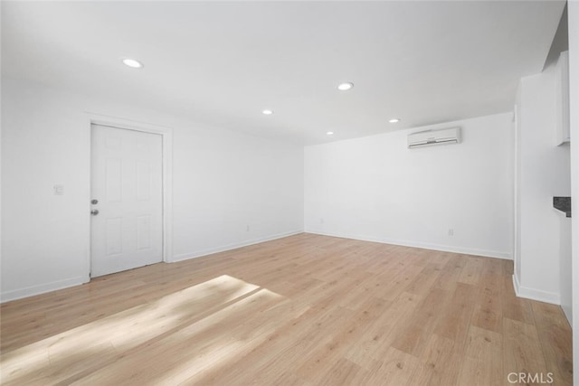 unfurnished room with a wall mounted AC and light hardwood / wood-style flooring