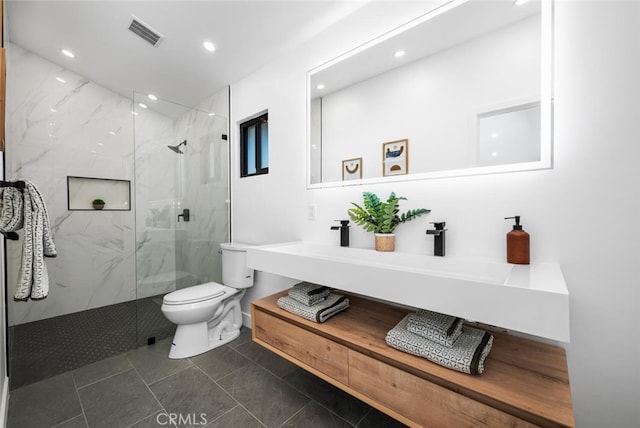 bathroom with toilet, tile patterned flooring, tiled shower, and vanity