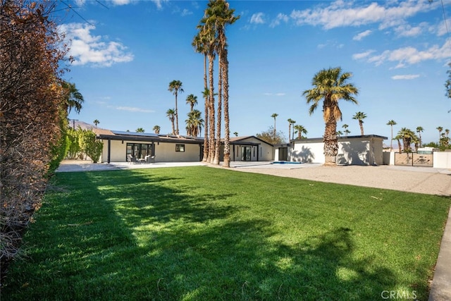 view of front of home with a patio area, a front lawn, an outdoor pool, roof mounted solar panels, and fence