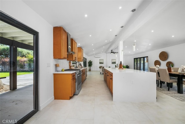 kitchen with stainless steel gas range, ceiling fan, vaulted ceiling with beams, wall chimney range hood, and sink