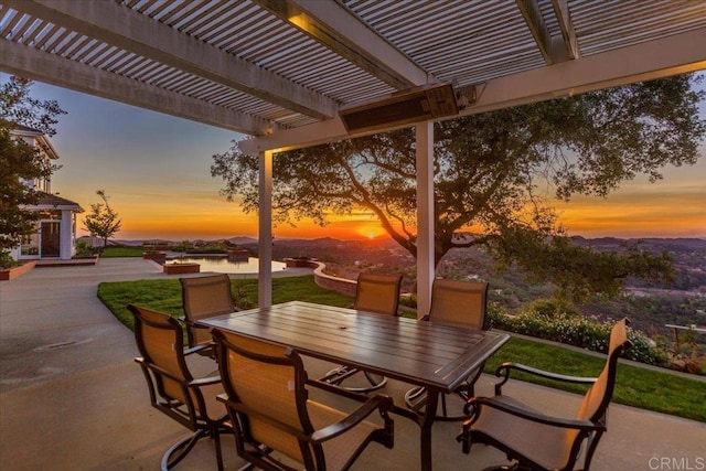 patio terrace at dusk with a water view and a pergola