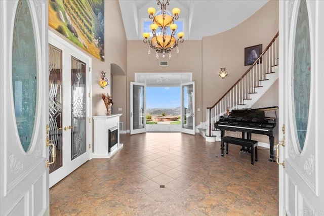 foyer featuring french doors, a towering ceiling, and a notable chandelier