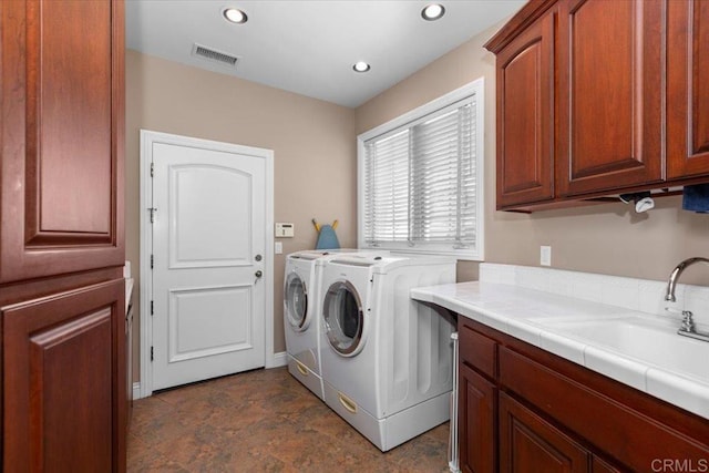 clothes washing area featuring cabinets, sink, and washing machine and dryer