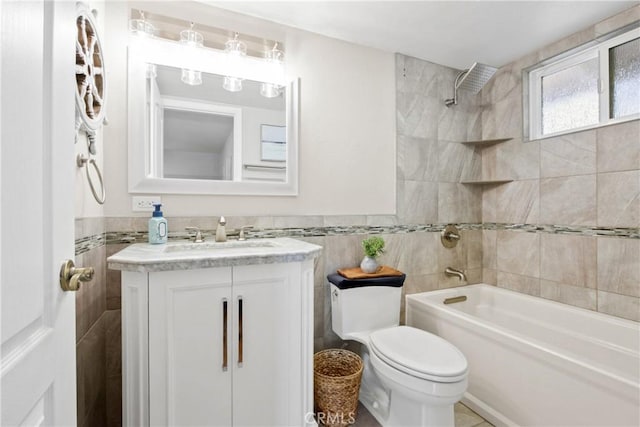 full bath featuring tile walls, shower / bath combination, toilet, wainscoting, and vanity