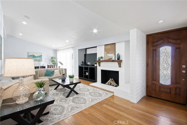 living room with vaulted ceiling, a fireplace, light wood-style flooring, and recessed lighting