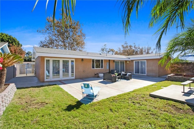 rear view of property featuring a patio area, a lawn, outdoor lounge area, and stucco siding