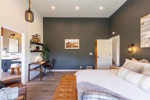 bedroom with a high ceiling, ensuite bath, dark wood-type flooring, and sink