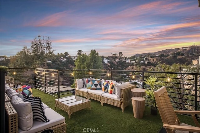 balcony at dusk featuring an outdoor living space