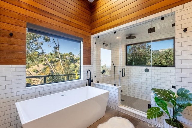 bathroom with separate shower and tub and tile walls