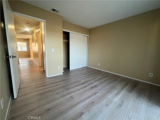 unfurnished bedroom featuring light hardwood / wood-style flooring and a closet