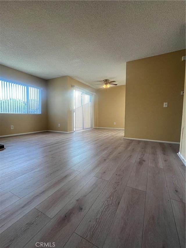 spare room featuring a textured ceiling, light wood-type flooring, and ceiling fan