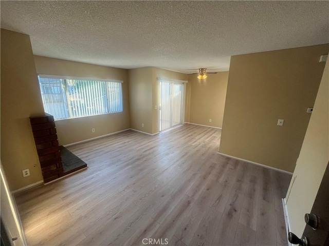 spare room with ceiling fan, light hardwood / wood-style floors, and a textured ceiling