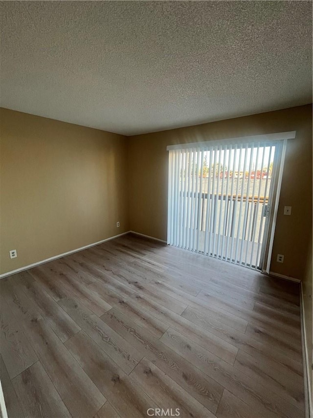 empty room with light hardwood / wood-style flooring and a textured ceiling