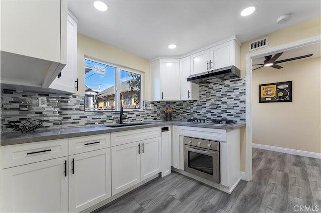 kitchen featuring decorative backsplash, appliances with stainless steel finishes, light wood-type flooring, ceiling fan, and white cabinetry