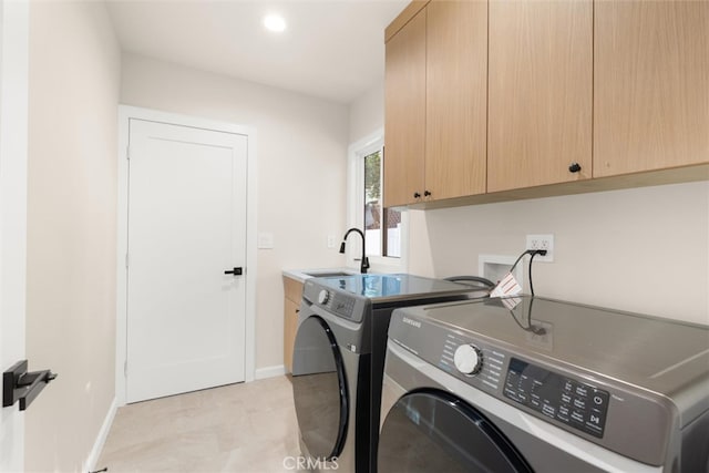 clothes washing area featuring sink, cabinets, and independent washer and dryer