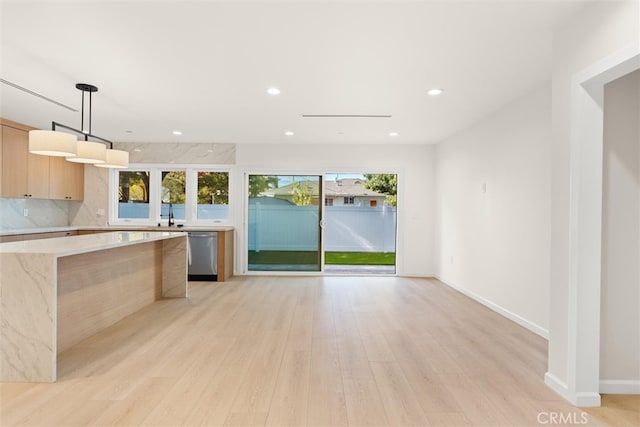 kitchen featuring a wealth of natural light, light brown cabinets, decorative light fixtures, and light hardwood / wood-style flooring