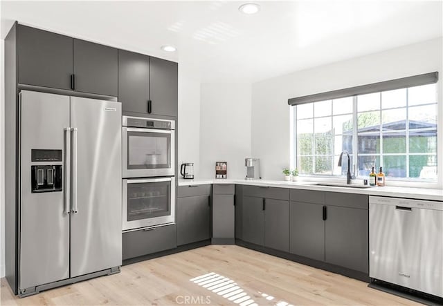 kitchen featuring gray cabinetry, sink, stainless steel appliances, and light hardwood / wood-style flooring