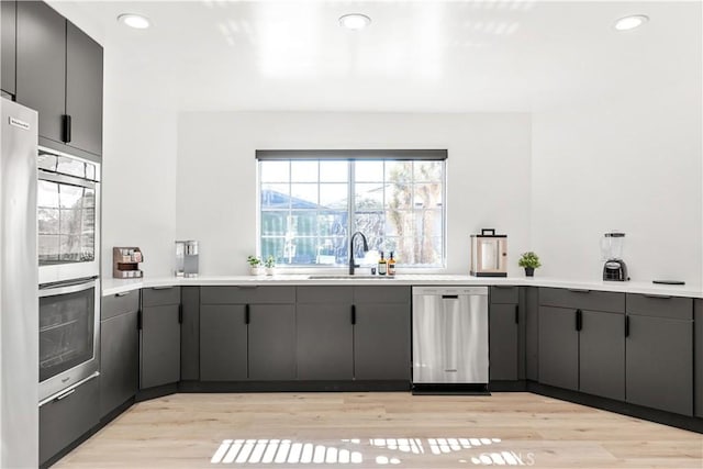 kitchen featuring light wood-type flooring, sink, and appliances with stainless steel finishes