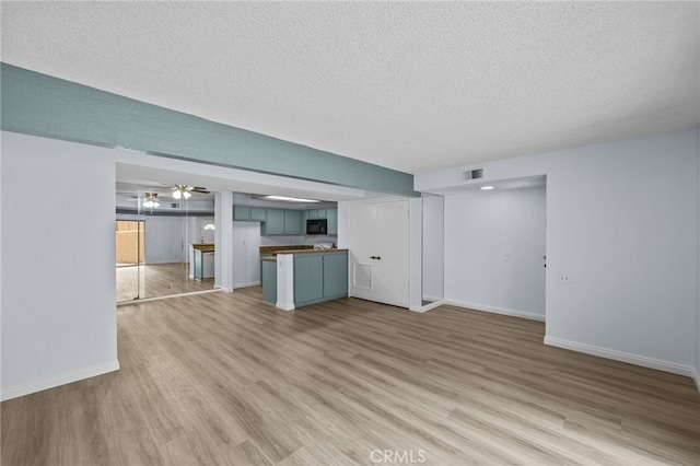 unfurnished living room with a textured ceiling and light hardwood / wood-style floors