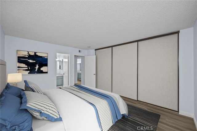 bedroom with a textured ceiling, a closet, ensuite bathroom, and wood-type flooring