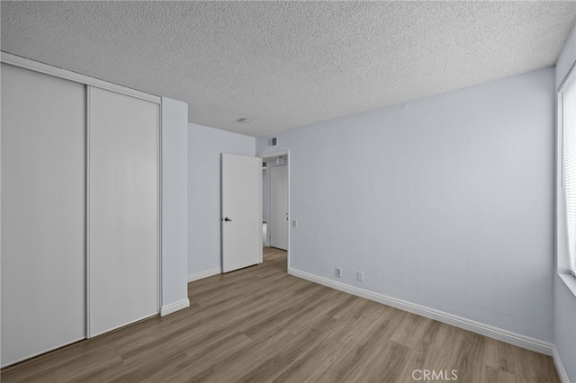 unfurnished bedroom with a closet, a textured ceiling, and light hardwood / wood-style flooring