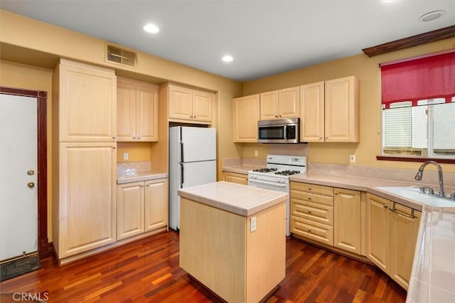 kitchen featuring white appliances, tile counters, a kitchen island, dark wood-type flooring, and sink