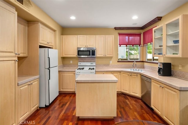 kitchen featuring tile countertops, stainless steel appliances, sink, dark wood-type flooring, and a center island