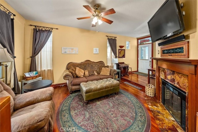 living room featuring ceiling fan, hardwood / wood-style floors, a high end fireplace, and a wealth of natural light