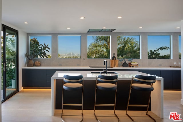 kitchen featuring a kitchen breakfast bar, sink, a kitchen island with sink, and light hardwood / wood-style flooring