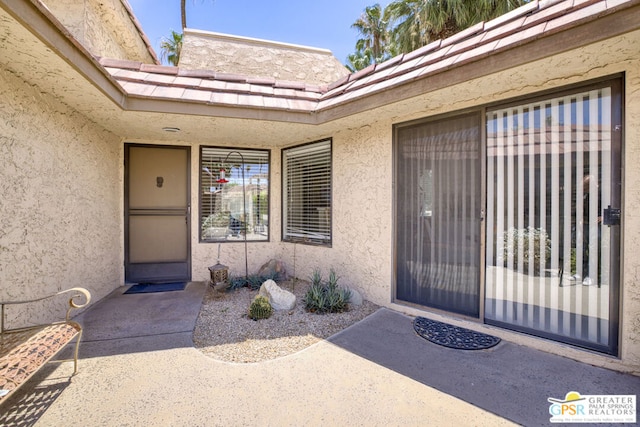 view of exterior entry with a patio area