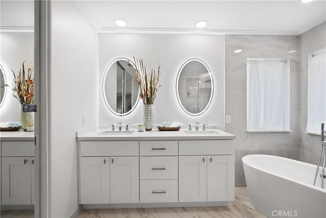 bathroom with a bathing tub, vanity, and ornamental molding