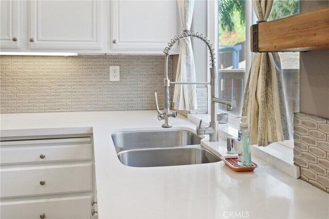 kitchen with decorative backsplash, white cabinetry, and sink