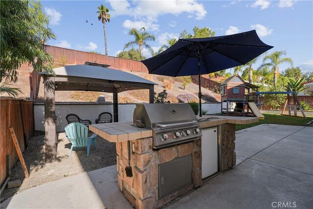 view of patio / terrace with an outdoor kitchen, a playground, and a grill