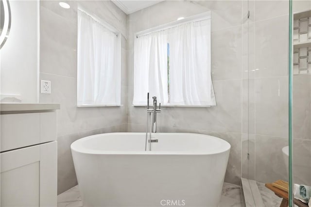 bathroom featuring a washtub and tile walls