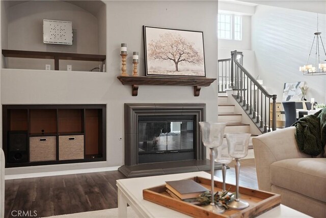 living room with hardwood / wood-style floors, a high ceiling, and an inviting chandelier