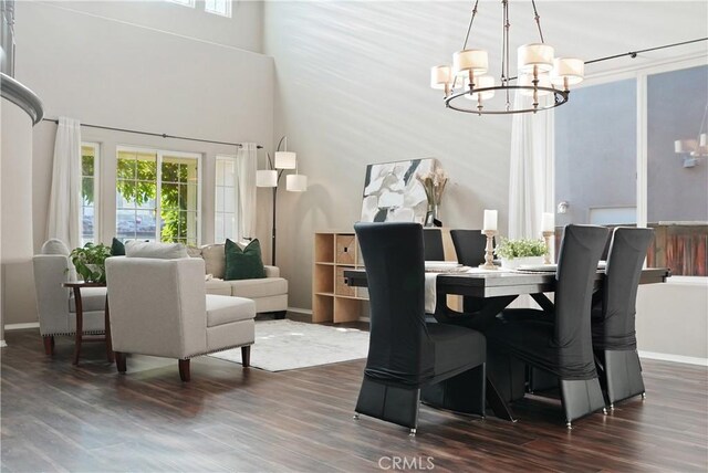 dining room with a towering ceiling, dark hardwood / wood-style flooring, and an inviting chandelier