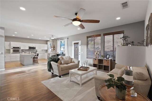 living room featuring light wood-type flooring and ceiling fan