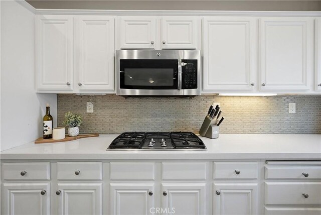 kitchen with decorative backsplash, white cabinetry, and appliances with stainless steel finishes