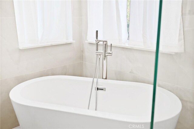 bathroom with a bath and tile walls