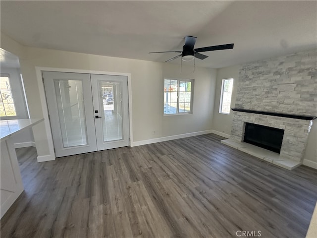 unfurnished living room featuring a fireplace, french doors, dark hardwood / wood-style floors, and ceiling fan