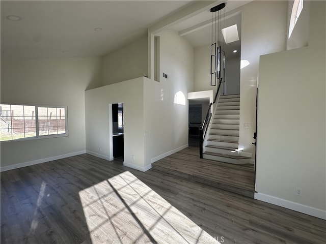 unfurnished living room with high vaulted ceiling and dark wood-type flooring