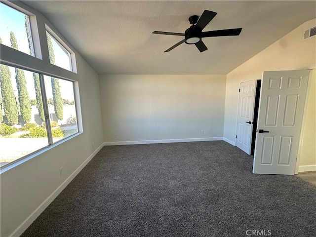 spare room with a wealth of natural light, ceiling fan, dark carpet, and lofted ceiling