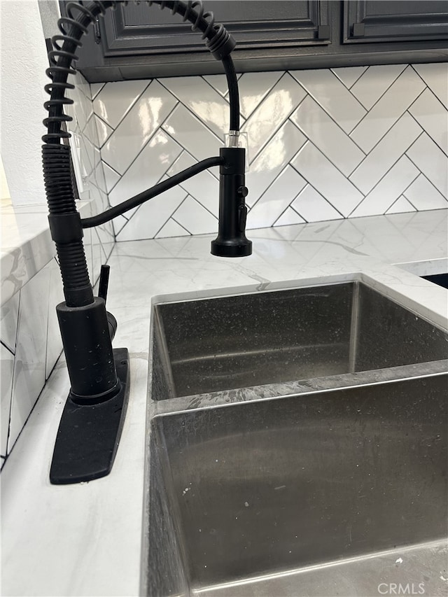 details with decorative backsplash, stone countertops, and sink