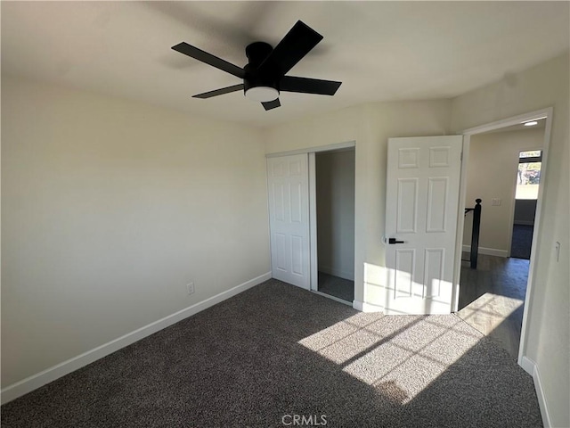 unfurnished bedroom featuring dark colored carpet, ceiling fan, and a closet