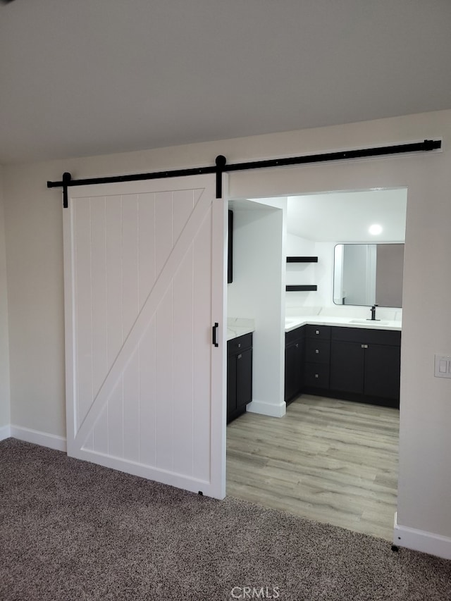 interior space featuring a barn door, sink, and light carpet