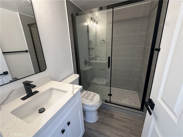 bathroom featuring hardwood / wood-style floors, vanity, toilet, and a shower with shower door