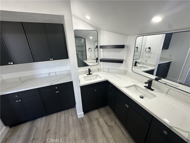 bathroom featuring vanity, hardwood / wood-style flooring, a shower with shower door, and lofted ceiling